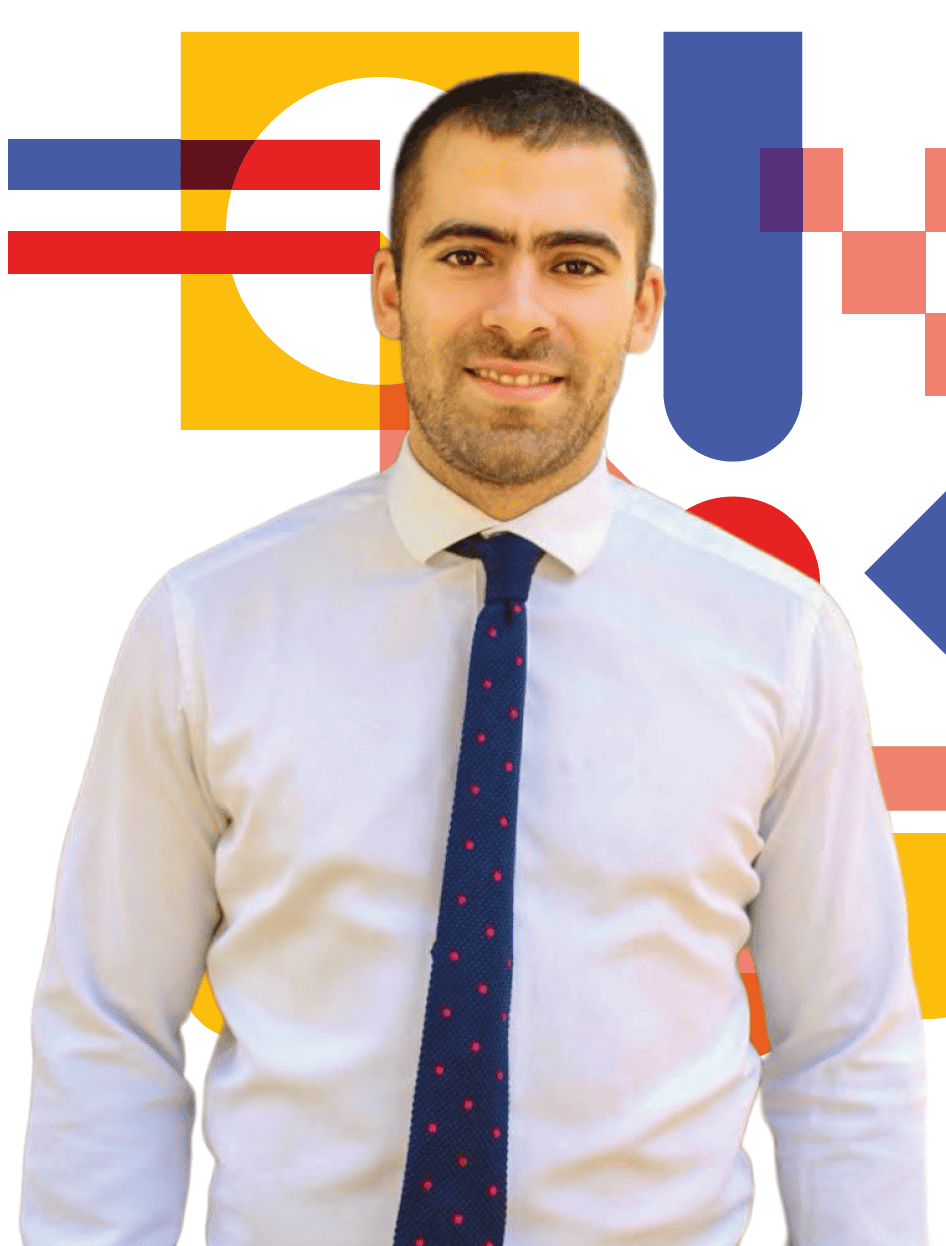 Un primer plano de un hombre profesional sonriente con una camisa blanca y una corbata azul con lunares rojos, de pie frente a un fondo gráfico abstracto geométrico colorido.